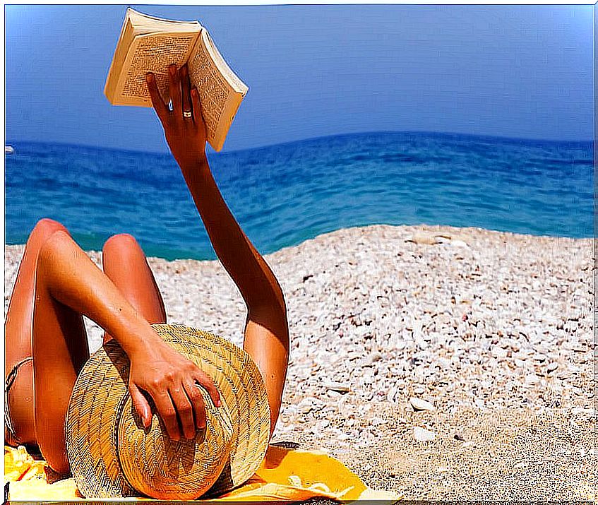 Woman lying on the beach reading a book