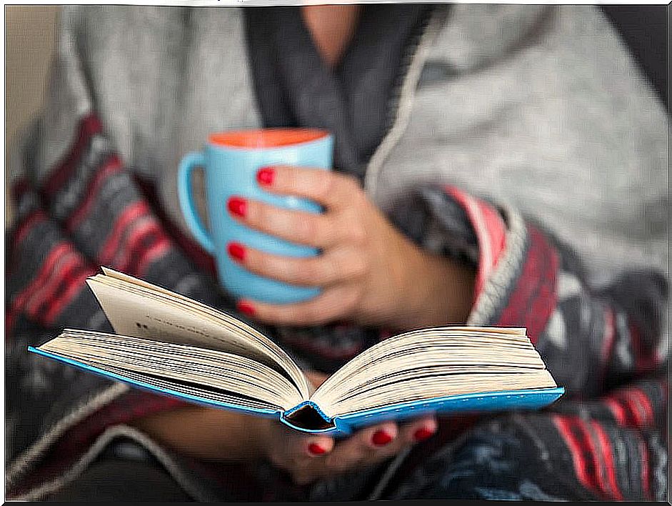 Woman reading a book with a cup of coffee to have a more productive day.