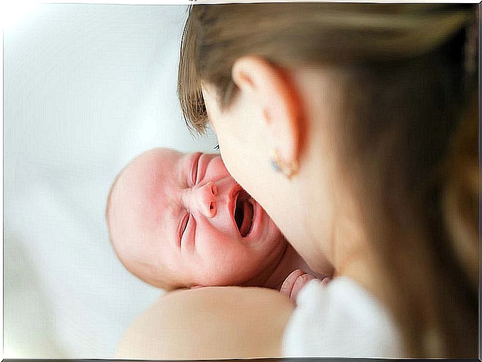 Crying baby in his mother's arms.