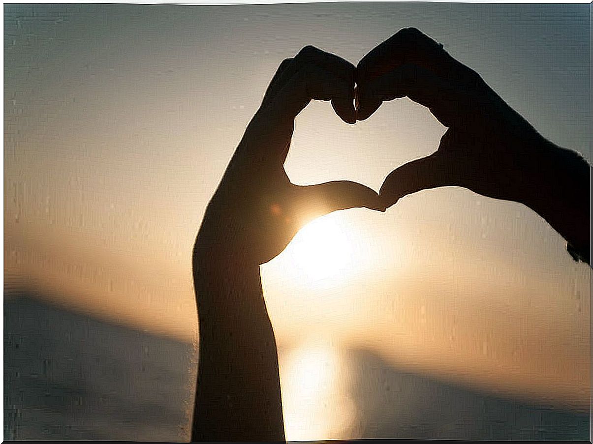 Hands forming a heart at sunset.