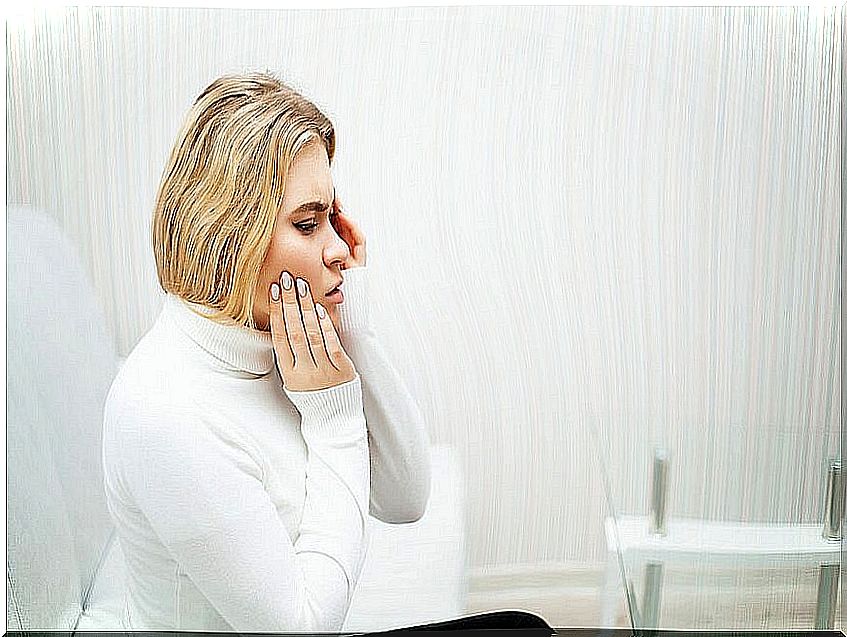 Blond woman touching her cheek because she has dental pain